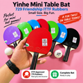 A hand holds a set of colorful mini table bats and a small ball against a pink background. The products are labeled as 729 Friendship ITTF Rubbers, shown in purple, green, red, blue, and black colors.